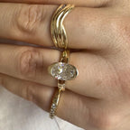 Top-down view of 2 CT oval cut lab grown diamond bezel ring worn on hand with gold stacking bands