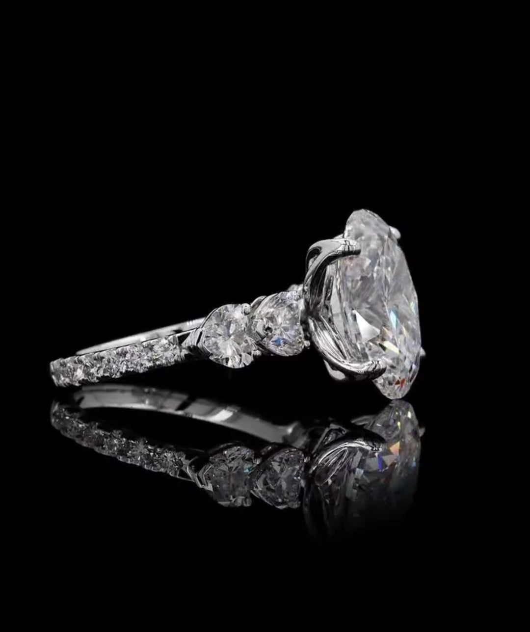 Perspective side view displaying the heart-cut shoulder stones and large oval center lab diamond