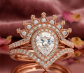 Front view of 2 CT pear lab diamond halo ring set with crown tiara and chevron band on rose gold velvet background