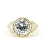 Front view of 4 CT round lab diamond three stone ring with milgrain bezel setting and trillion side diamonds.