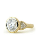 Angled view of 4 CT round lab grown diamond bezel ring with satin yellow gold band.