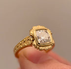 Angled view showing hand-engraved leaf pattern on yellow gold shank of 4 CT cushion ring.