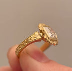 Side profile shot focusing on intricate leaf hand-carving and milgrain edge of yellow gold band.