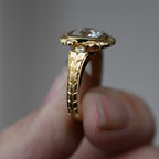 Side perspective highlighting hand-carved botanical leaf pattern along yellow gold shank.