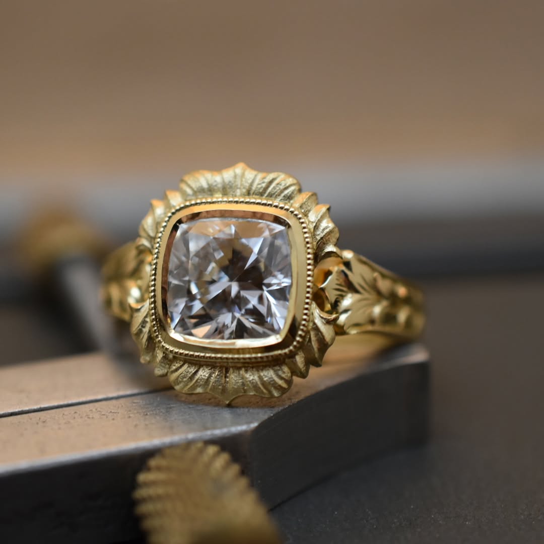Macro studio view of 4 CT cushion cut lab grown diamond scalloped bezel ring on jeweler bench.