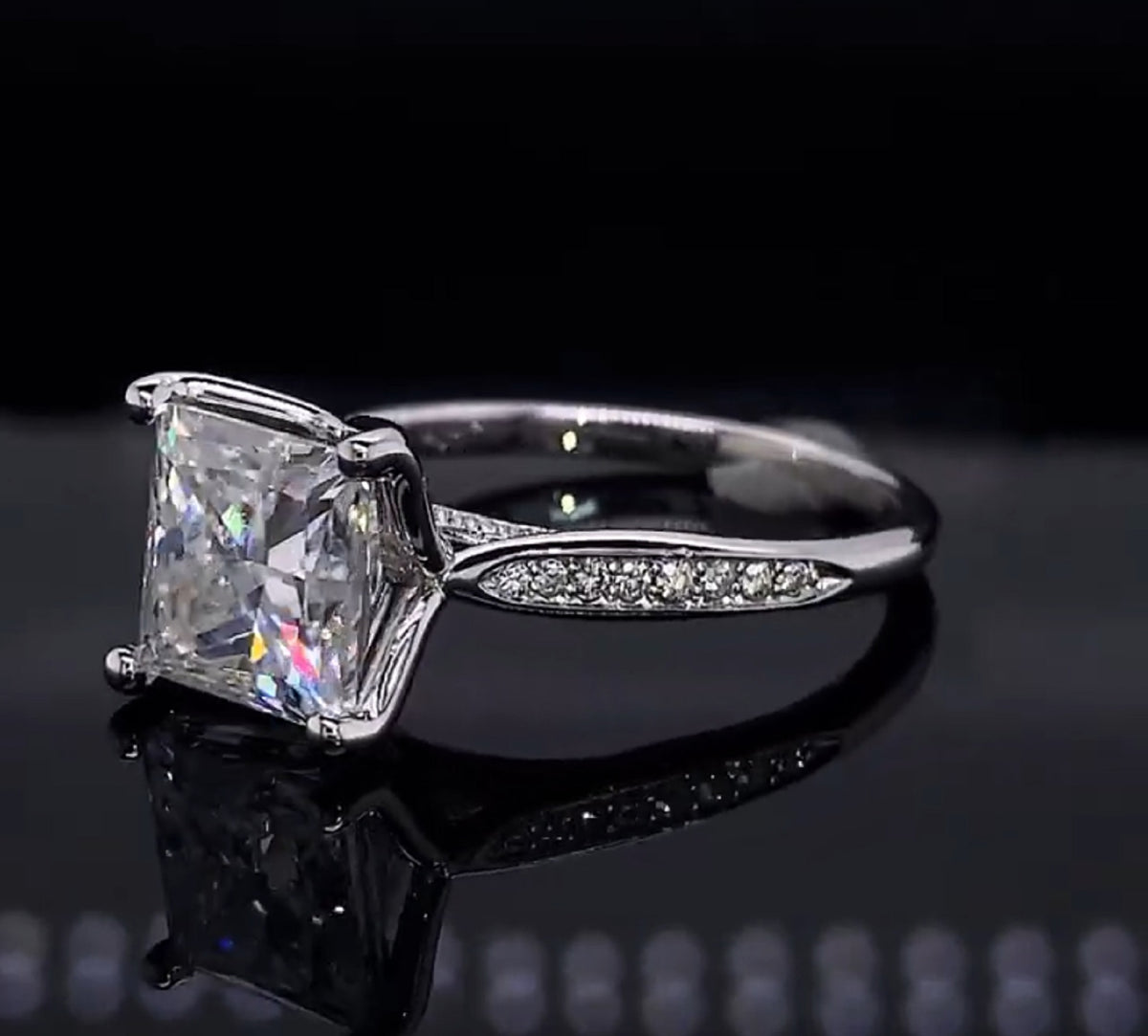 Three-quarter view of white gold 3 carat princess cut lab diamond ring on dark surface