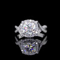 Top-down view of a 2 CT cushion cut lab grown diamond ring with a halo and twisted band, reflected on a black surface.