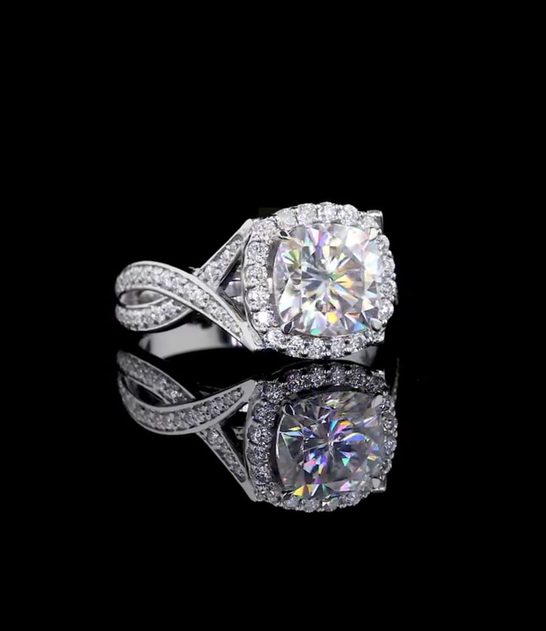 Angled top view of a cushion cut diamond halo engagement ring highlighting the sparkling infinity pavé band.