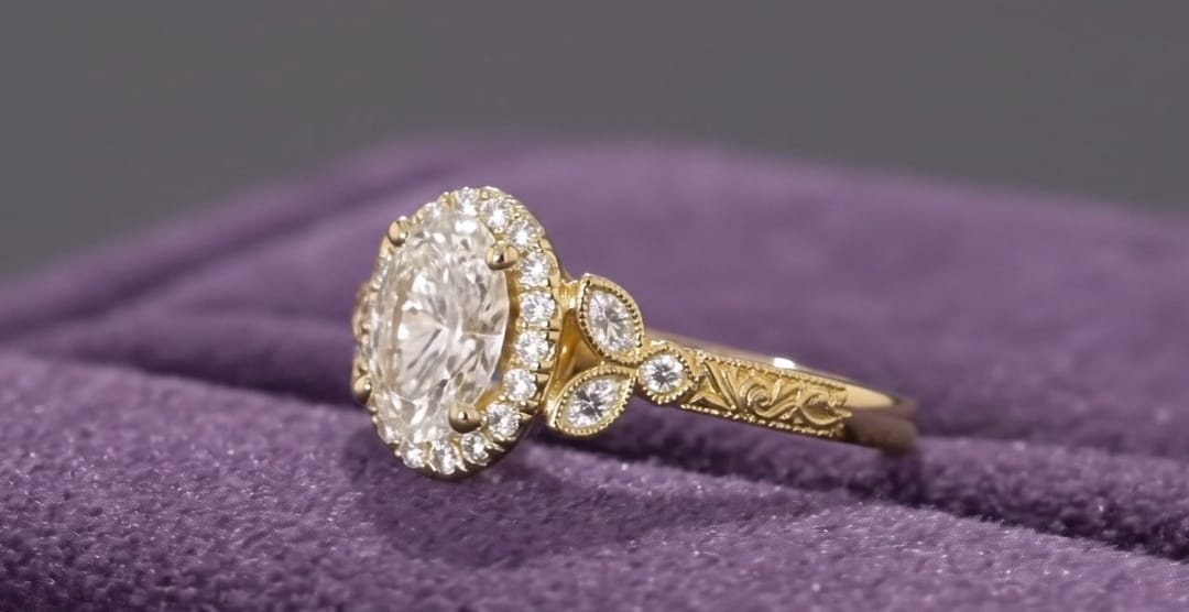 Side profile view of a vintage style 2ct oval lab grown diamond ring in yellow gold showing engraved band details.
