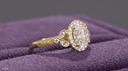 Angled front view of an antique-inspired 2 carat oval lab grown diamond ring with intricate yellow gold engraving.