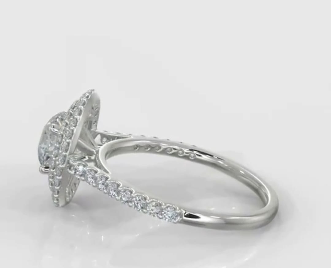 Side profile of a round cut double halo engagement ring showing the elevated prong setting and pave diamond band.
