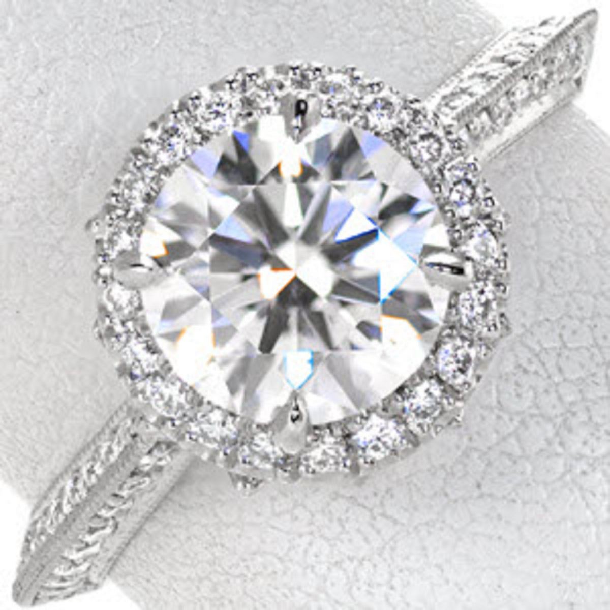 Top-down close up of a 3 carat round cut lab grown diamond halo engagement ring with a milgrain pave band.