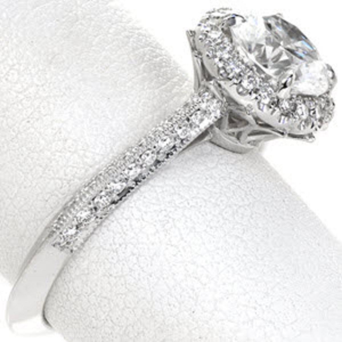 Angled view of a 3 carat lab grown diamond engagement ring highlighting the pave set diamonds, milgrain edges, and detailed basket.