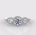 Top-down view of a 2 CT round cut lab grown diamond ring with two pear-shaped side stones and continuous halo settings.