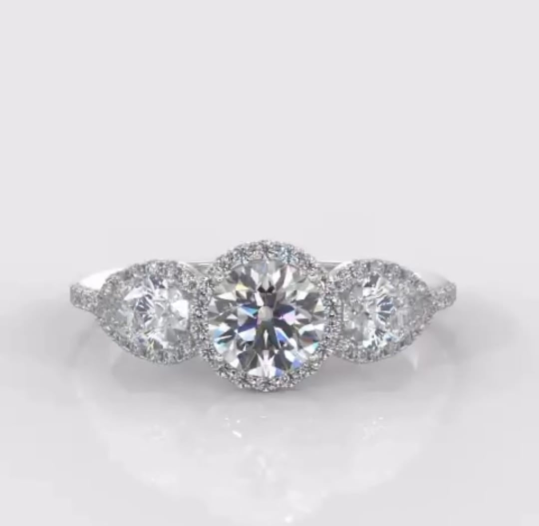 Top-down view of a 2 CT round cut lab grown diamond ring with two pear-shaped side stones and continuous halo settings.