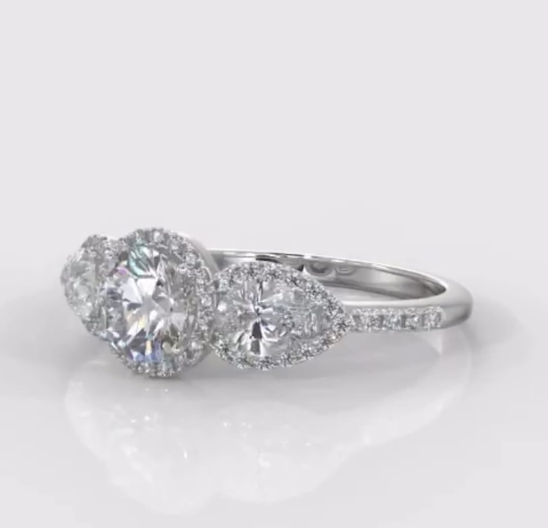 Angled front view of a stunning three-stone halo lab grown diamond engagement ring with a pave diamond band.