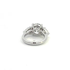 Back angle view of a three-stone diamond ring showcasing the open gallery setting and solid white metal band.
