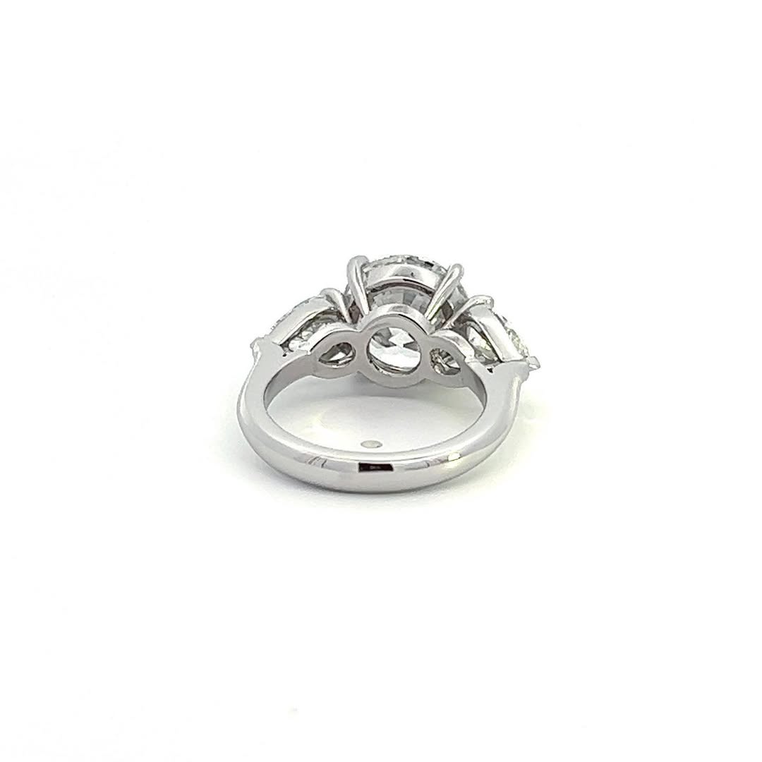 Back angle view of a three-stone diamond ring showcasing the open gallery setting and solid white metal band.