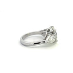 Angled side view of a classic three-stone engagement ring with a round center diamond and polished cathedral setting.