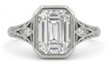 Top-down view of an emerald cut lab diamond ring showing intricate side diamond accents and filigree metalwork.