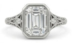 Top-down view of an emerald cut lab diamond ring showing intricate side diamond accents and filigree metalwork.