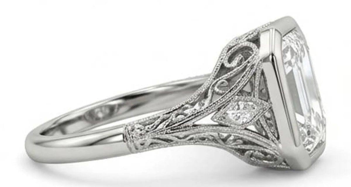 Side profile of a vintage style engagement ring showcasing intricate filigree, milgrain details, and an elevated bezel setting.