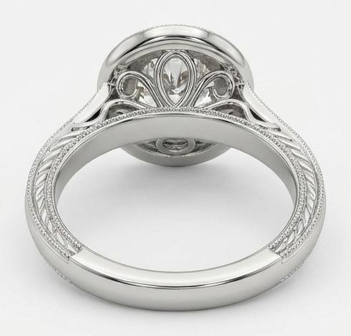 Under-gallery view of a white gold diamond engagement ring showing intricate filigree scrollwork and an engraved band beneath the center stone.
