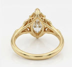 Underneath view of a marquise cut lab grown diamond engagement ring showing the leaf scrollwork and yellow gold setting structure.