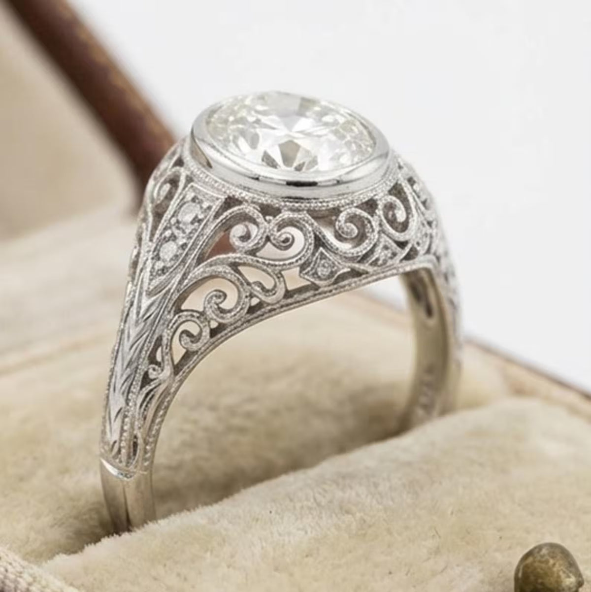 Perspective view of an Art Deco 3 CT oval cut lab grown diamond bezel ring in a vintage ring box.