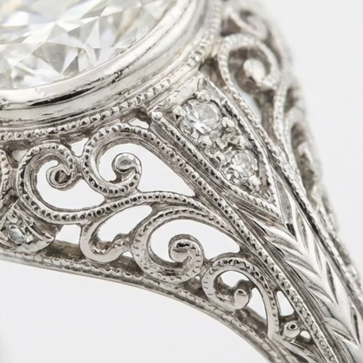 Close-up detail of hand-carved milgrain, filigree scrollwork, and diamond accents on a vintage lab diamond ring band.