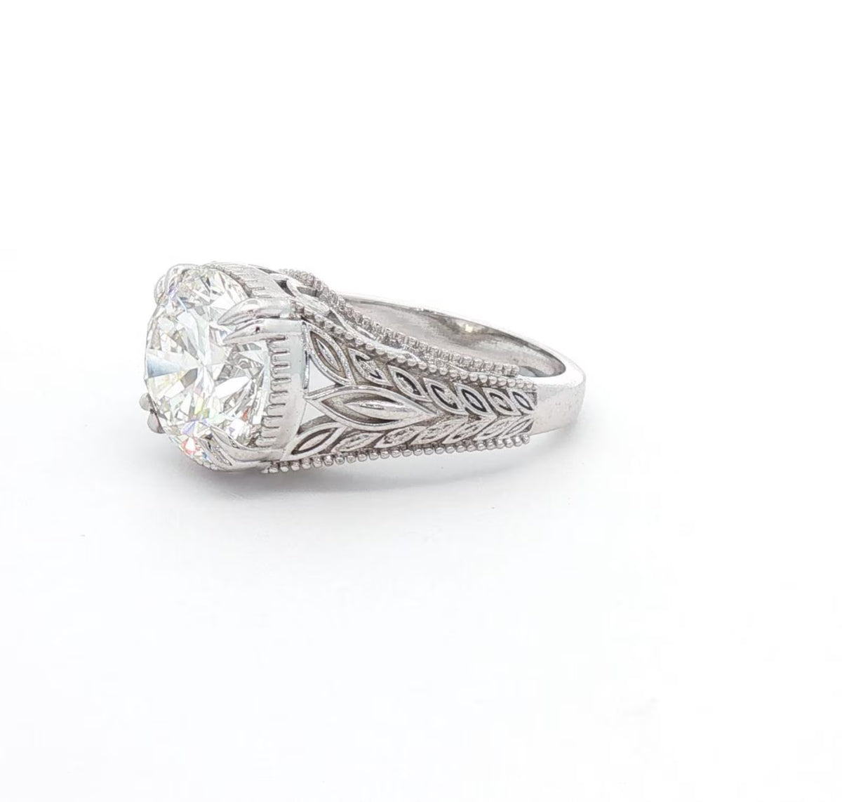 Perspective angle highlighting the intricate milgrain and leaf filigree pattern on white gold band.