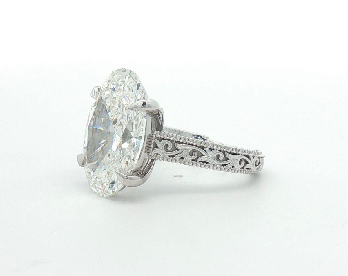 Angled view showing milgrain borders and hand-carved scroll engraving on white gold ring