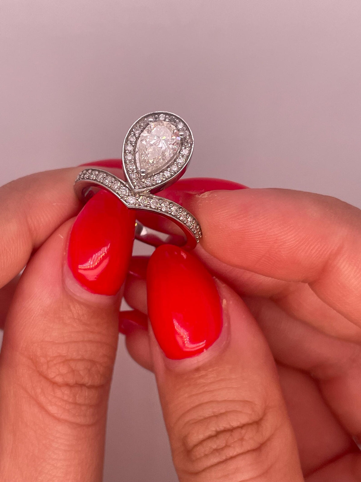 Front view of a 2 CT pear cut lab grown diamond halo ring on a curved chevron pavé band.