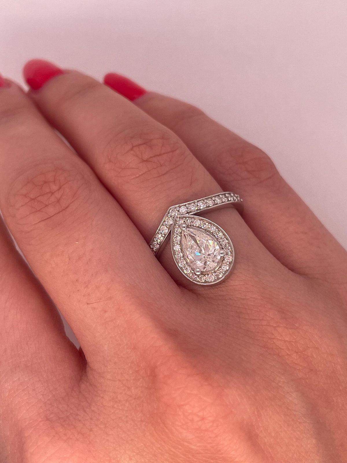 2 CT pear cut lab grown diamond halo engagement ring worn on hand.