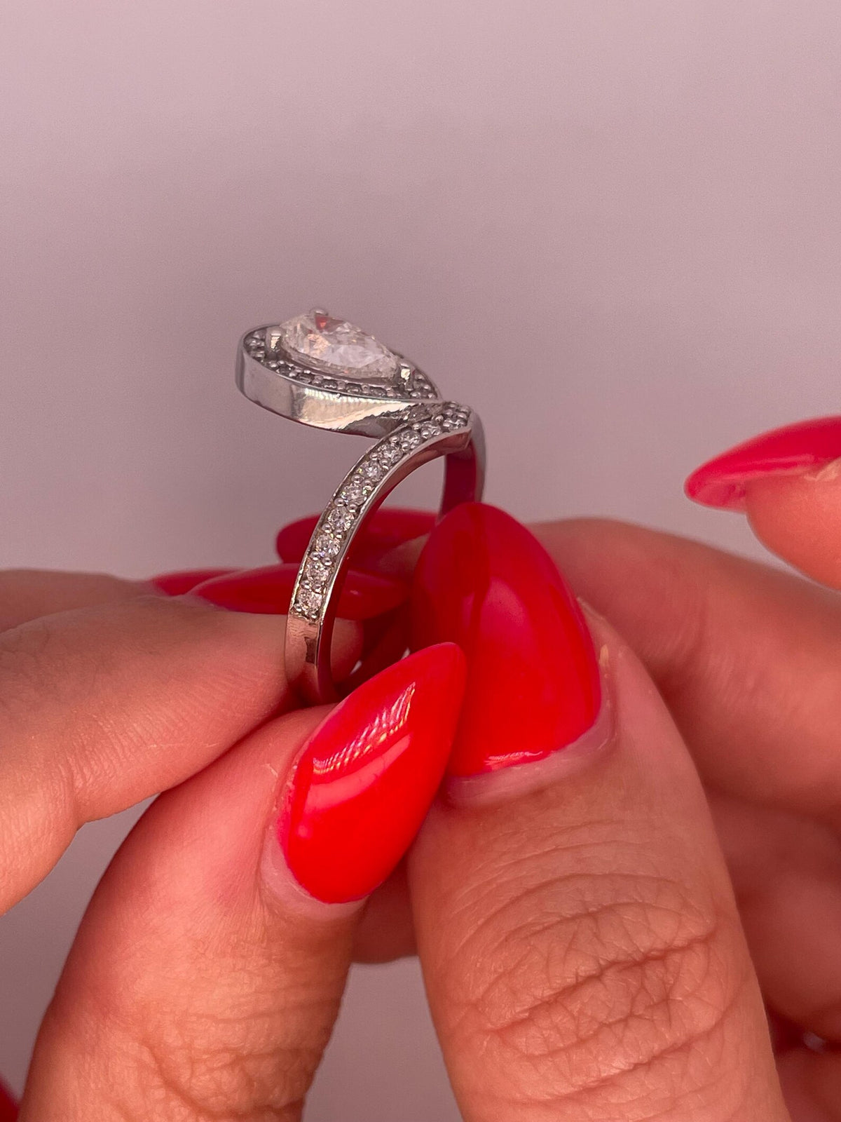 Side profile view showing halo setting and side pavé band detail of pear cut diamond ring.