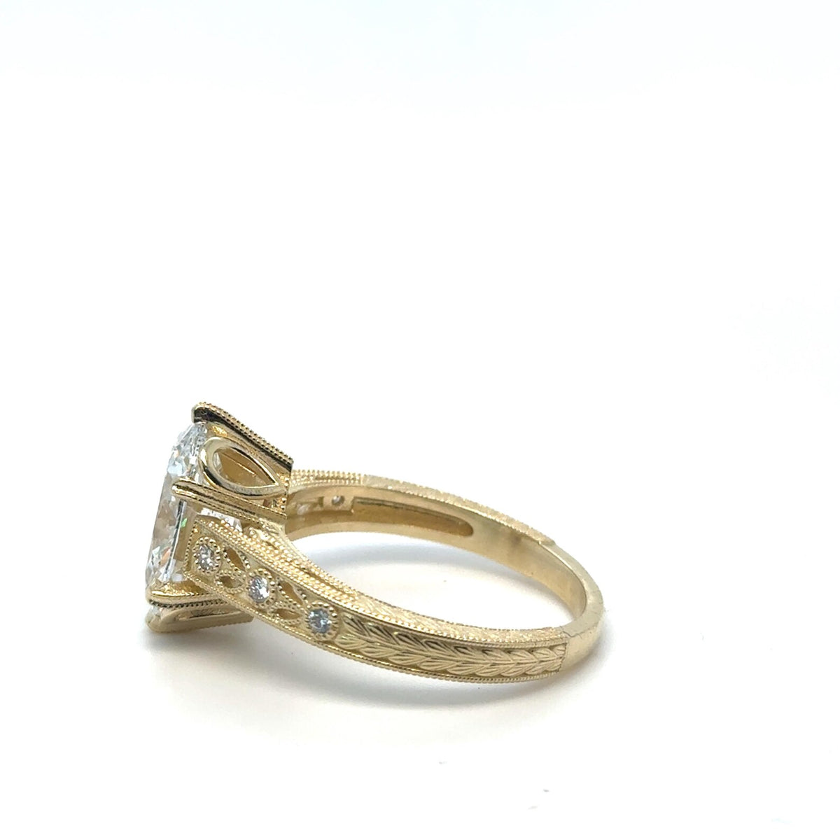 Side angle showing engraved band with milgrain edges and accent diamonds on 3 CT oval diamond ring.