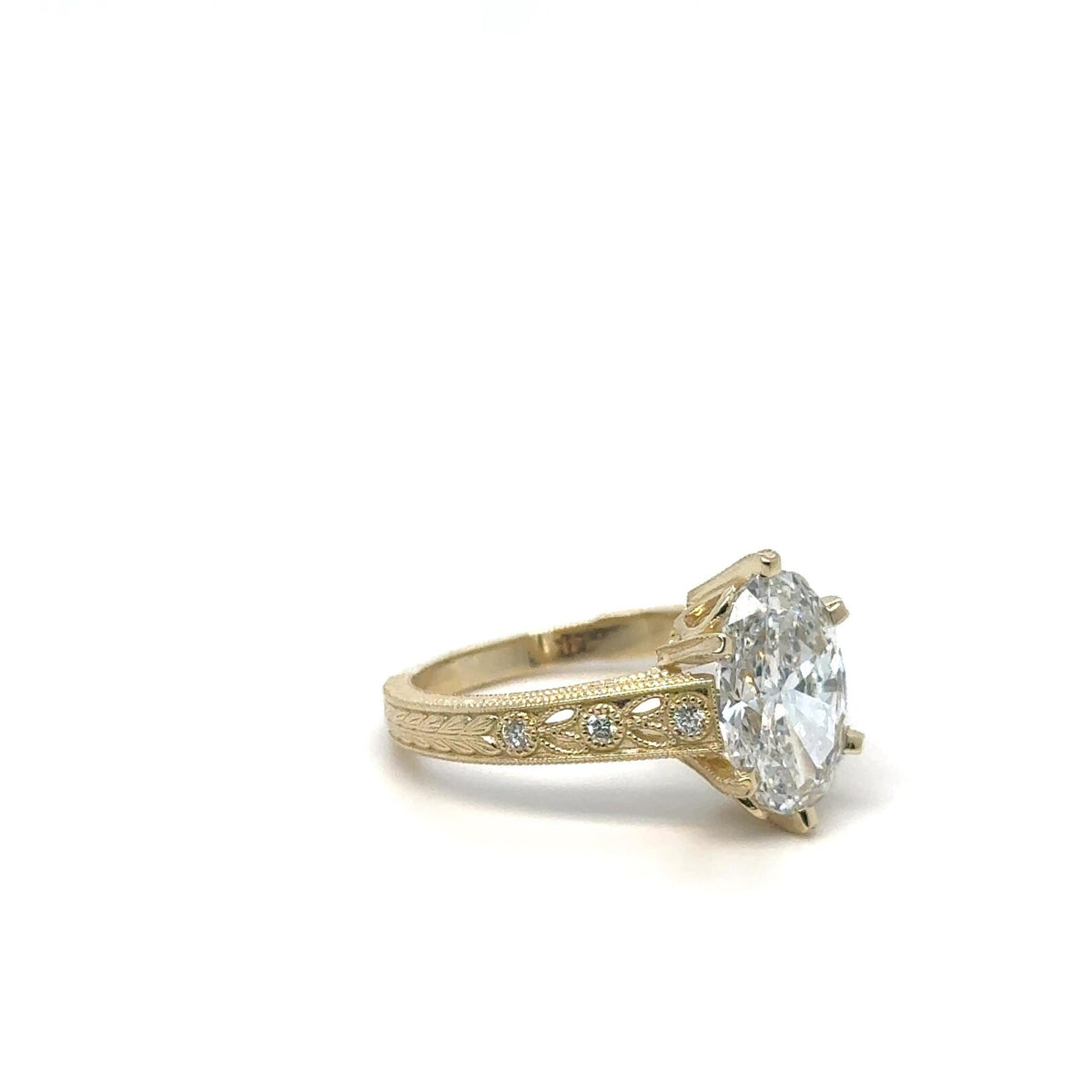 Perspective view of 3 carat oval lab grown diamond ring on carved yellow gold band.