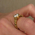 Side profile angle of a 2 CT round lab grown diamond bezel engagement ring worn on a finger.