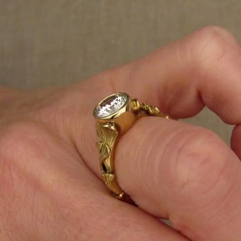 Side profile angle of a 2 CT round lab grown diamond bezel engagement ring worn on a finger.