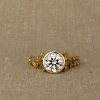 Direct top view showing round brilliant lab grown diamond set in a sleek yellow gold bezel frame.