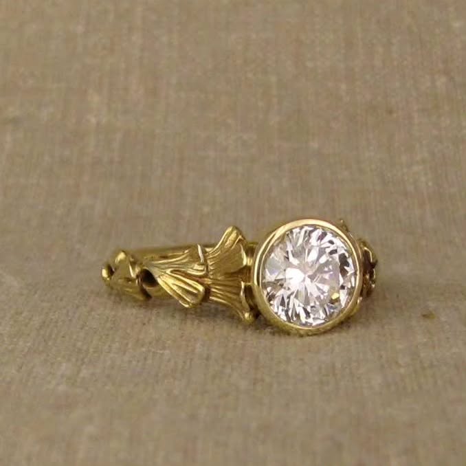 Angled detail of a round cut lab diamond ring with fan-like leaf shoulder motifs.