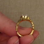 Full circular profile view of an 18K yellow gold bezel set round diamond ring held by hand.