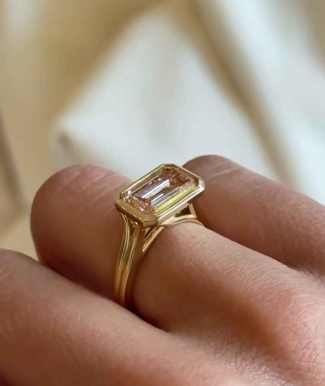 Side profile of yellow gold East-West pink emerald cut diamond ring showcasing split shank cathedral setting.
