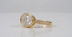 3 carat east-west oval lab grown diamond ring in yellow gold bezel setting with pavé band side angle view.