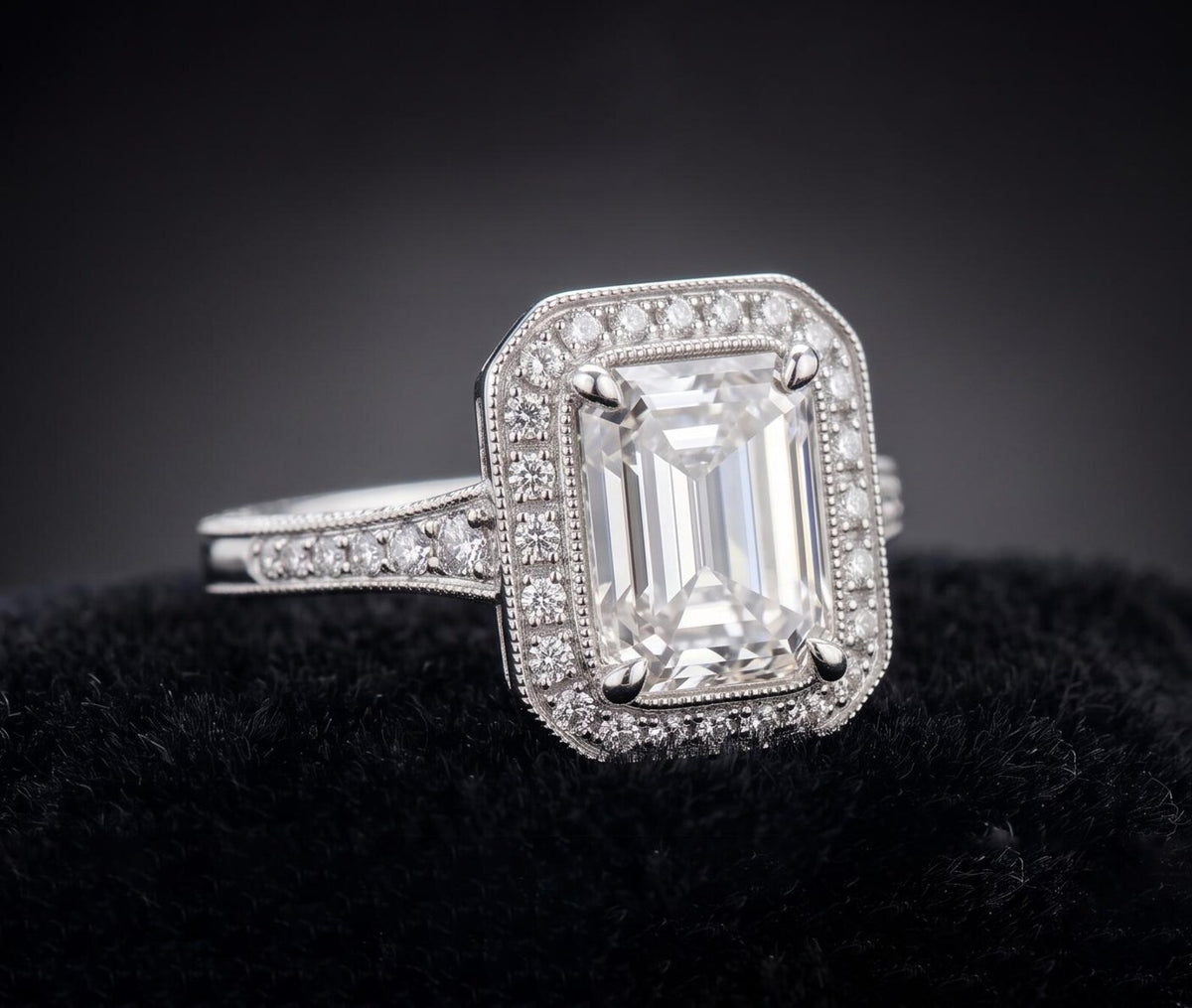 Angled view of 3 carat emerald cut lab grown diamond engagement ring with milgrain-bordered halo and pavé band.