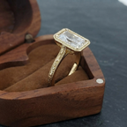 Angled side view of a vintage-style 3ct radiant cut diamond engagement ring sitting inside an open heart-shaped wooden ring box.