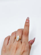 Close-up display of 3 carat marquise cut lab diamond ring set in gold on a model's finger.