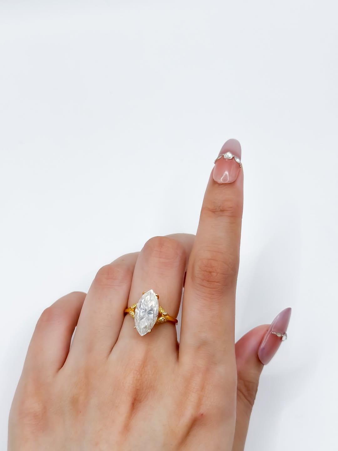 Close-up display of 3 carat marquise cut lab diamond ring set in gold on a model's finger.