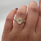 Close-up on hand wearing a 2 CT oval cut lab grown diamond bezel engagement ring in yellow gold.