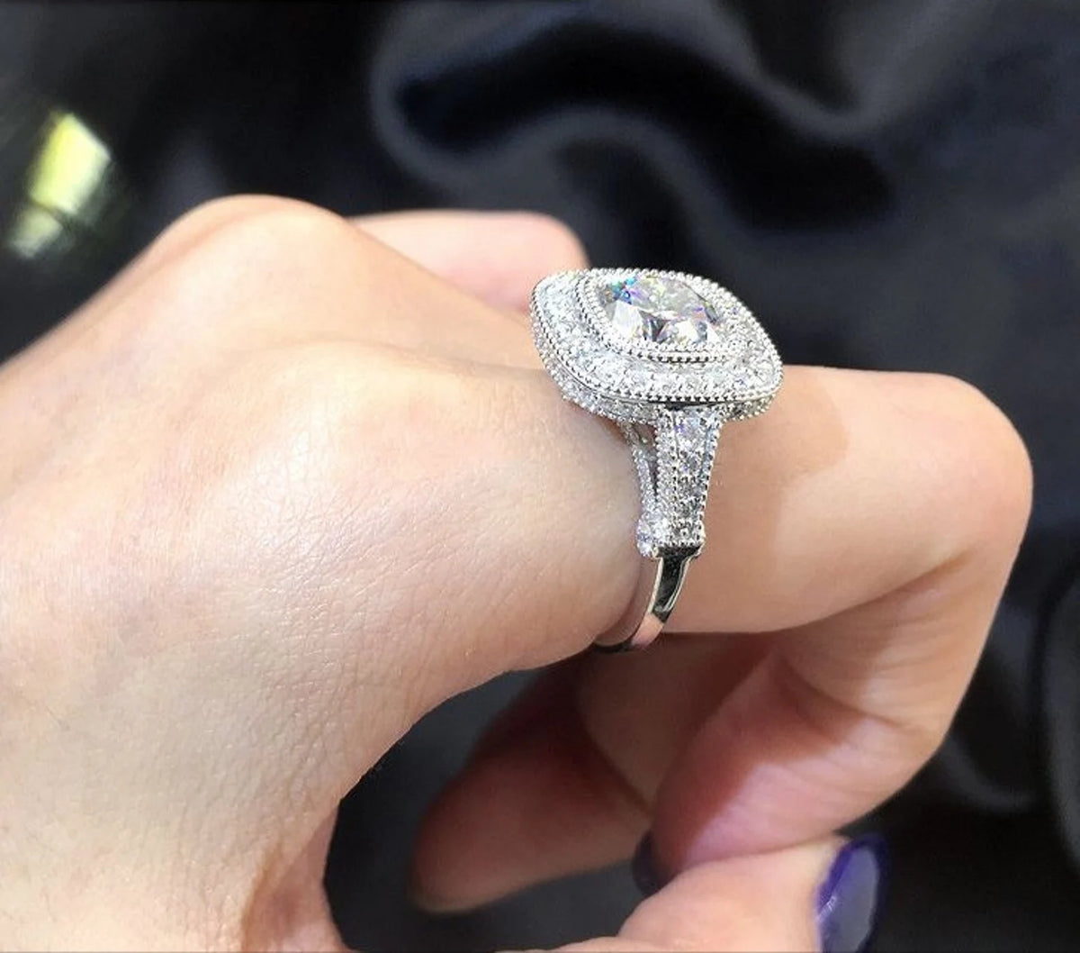 On-hand side angle view of cushion cut lab diamond engagement ring highlighting high cathedral setting and profile sparkle.